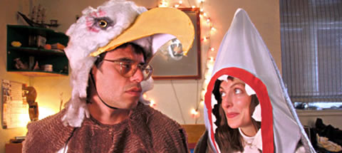Jemaine Clement, disfrazado de águila, resistiendose a los encantos de Loren Horsley en su atuendo tiburonil